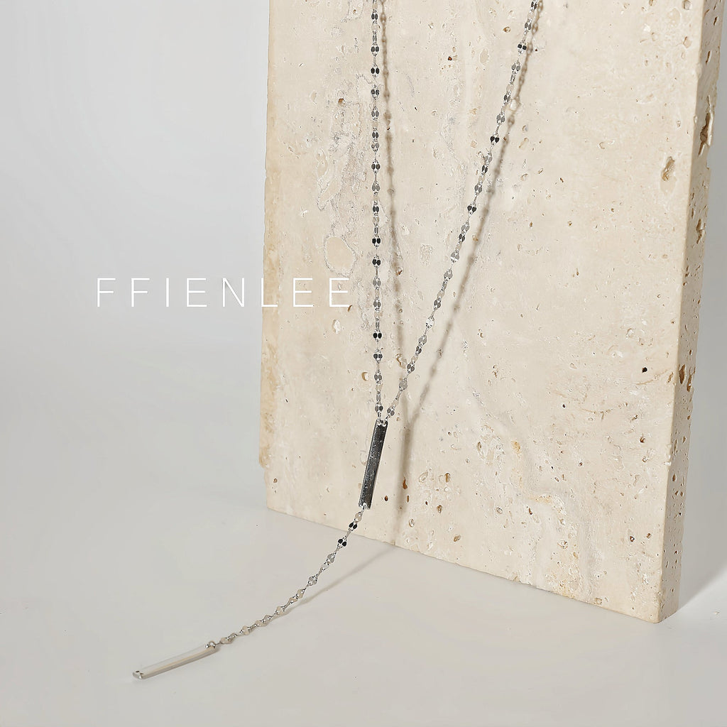 FFIENLEE 925 sterling silver Y-lariat tile chain necklace with double bar pendant in rhodium silver tone, draped against a textured cream travertine stone surface, showing full chain length, Y-drop, and both bar pendants, light grey background, FFIENLEE branding
